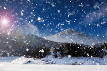 Christmas background with snowy fir trees and mountains in heavy blizzard.