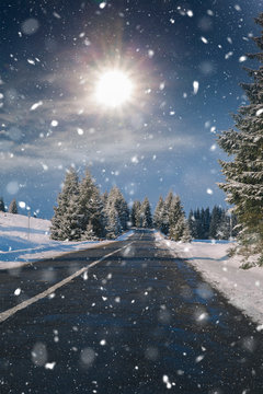 Christmas background with snowy fir trees and mountains in heavy blizzard. © belyaaa