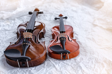 Two violins put on grunge surface background,show different size of stringed instrument,blurry light around