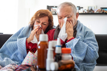 Elderly couple sitting on the sofa and blow their nose