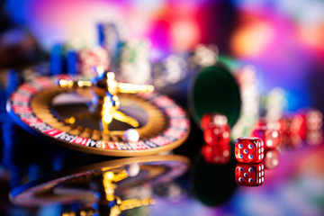 Casino theme.  Gambling games. Roulette, dice and poker chips on a colorful bokeh background.