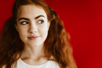 red-haired brown-eyed beauty - a girl with a sweet smile and a sly look, squinted at the side. background red-brown