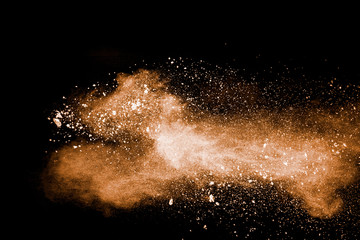 Freeze motion of brown dust explosion.Stopping the movement of brown powder.Explosive brown powder on black background.