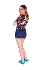 Beautiful young woman standing in shorts from the back