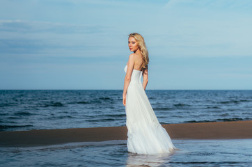 Fototapeta na wymiar Portrait of young blond bride staying among the water