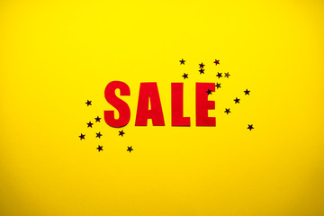Sale in red letters on a yellow background with confetti, flat lay. Black Friday concept. 