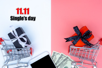 Online shopping of China, The shopping cart and Christmas boxes with black ribbon and smartphone and banknote on a pink and white background with copy space for text. 11.11 single's day sale concept