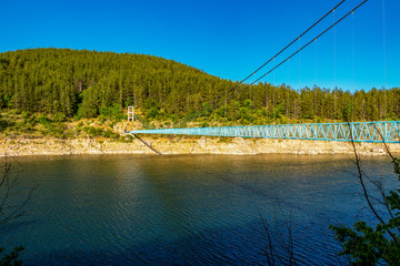 Obraz na płótnie Canvas Kardzhali Reservoir with the suspension bridge between the villages Suhovo and Duzhdovnitsa in Kardzhali Municipality, Bulgaria