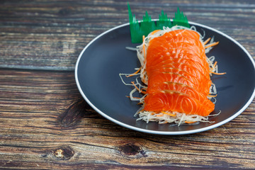 Salmon slices in a black plate on a wooden table