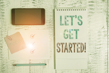 Writing note showing Let S Is Get Started. Business concept for to begin doing or working on something you had started Square spiral notebook marker smartphone sticky note on wood background