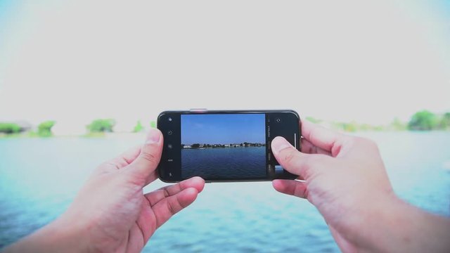 Slow motion of human hand using smartphone to photograph beautiful landscape