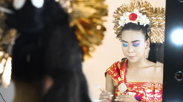 Balinese dancer coloring her eyelids in makeup room. Shot in 4k resolution