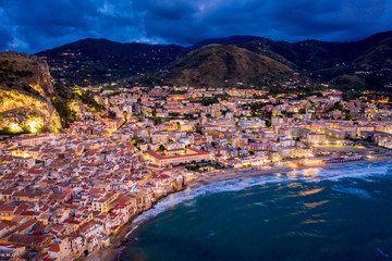 Panorama view on night cityscape of Cefalu from the sea. Tyrrhenian Sea. Sicily, Italy