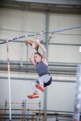 Pole vaulting indoors - young sportive woman falling down after the jump