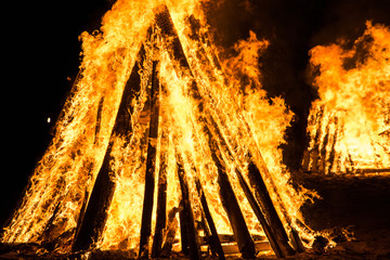 Cone shaped bonfire with big flames and wood