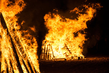Cone shaped bonfires with big flames and wood