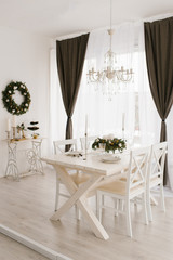 Dining set white wooden table with chairs in a bright living room decorated for Christmas and New Year in a classic style