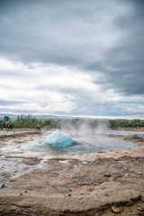 Geysir erupting in Iceland. Famous geyser on a cloudy day