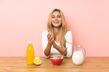 Young blonde woman having breakfast milk applauding
