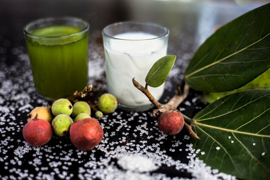 Best drink remedy to control weight on the black glossy wooden surface consisting of Banyan Tree fruit juice well mixed with milk and some sugar. Shot of all ingredients on surface.Horizontal shot.