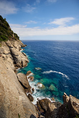 cliffs near Portofino, Italy, a crytal clear sea and a blue sky with some clouds