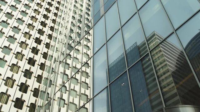Skyscrapers reflections with green glass windows at business district in Paris, slow steadicam movement pan left, close-up shot with reflections. Futuristic modern buildings in Blue Sky. 4K UHD.