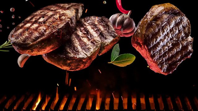 Grilled pieces of steak with spices and salt slowly fall over the barbecue grill, coals slowly burn.
