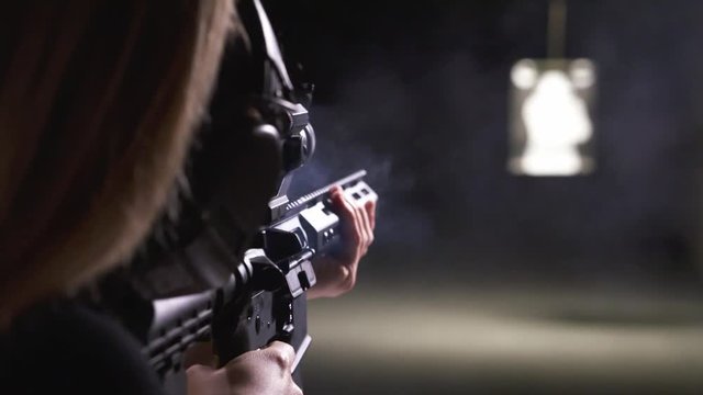 Slow Motion Over the Shoulder View of Woman Firing at Target in Shooting Range