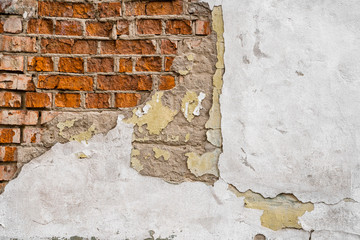 Cracked concrete vintage brick wall. Cracked putty on the wall and brick that looks through the...