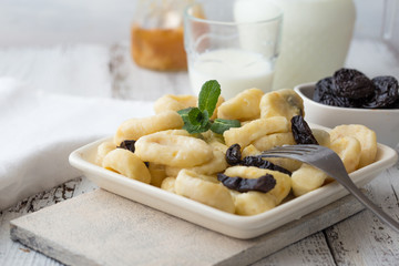 Lazy pierogi dumplings with sour cream and dry plums. and glass of milk.  Italian gnocchi