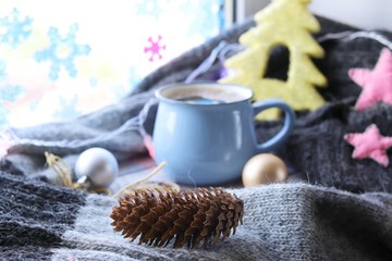 Obraz na płótnie Canvas Cup of coffee, Christmas decor, spruce branch, balls, woolen plaid on the window background, home comfort concept, seasonal winter celebrations