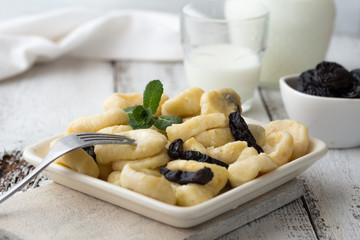 Lazy pierogi dumplings with sour cream and dry plums. and glass of milk.  Italian gnocchi