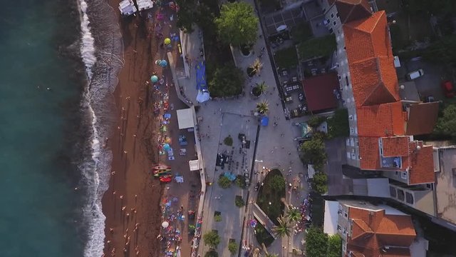 Aerial shot of the waves flood the beach of a small Mediterranean town Petrovac, Montenegro.