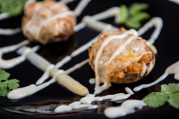 Detail of a spanish tapa, bechamel and sauce on black plate