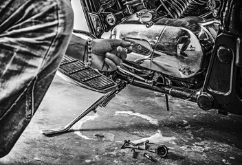 man repairing a classic motorcycle in black and white