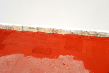 Waterproofing the terrace of a building with red acrylic rubber paint to solve infiltration and...