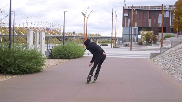 Inline skater in black doing stylish tricks on skates in slow motion