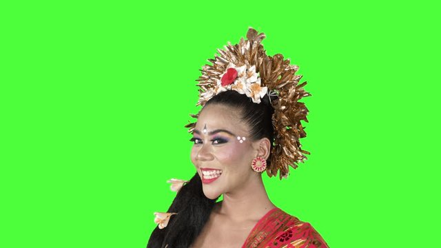 Beautiful friendly balinese dancer in traditional costume smiling at the camera while standing in te studio. Shot in 4k resolution with green screen background