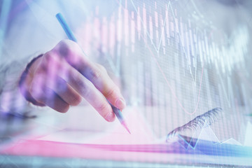 Financial forex graph displayed on hands taking notes background. Concept of research. Double...