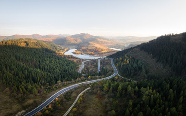 Fototapeta na wymiar Aerial drone view over the autumn mountains with mountain road serpentine, river and forest. Landscape photography
