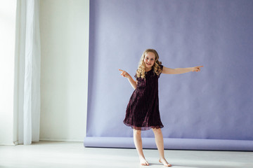 Girl in a dress dances to the music alone in the room