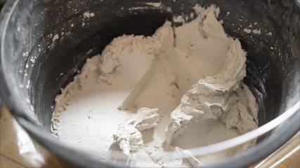 trowel with bucket of filler isolated on white background. White mortar in a black bucket.