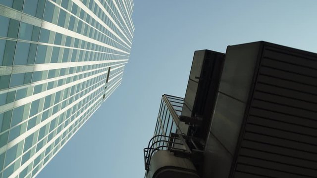 Three Skyscrapers with green glass windows at business district in Paris, looking up low angle barel roll, wide shot with reflections. Futuristic modern building in Blue Sky. 4K. White green black.