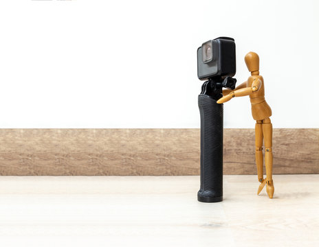 Wooden dummy standing on the toes looking through a photo and video camera