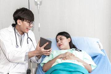 Fototapeta premium Asian male doctor Hold a genuine tablets Show information to patiens Makes the patient satisfied and happy, to health care and health insurance concept.