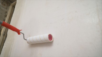 primer on the brick wall with a roller. Brick wall repair with putty. Applying a primer on a brick wall.