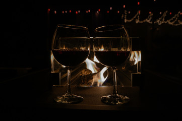 Glasses of red wine in front of fire
