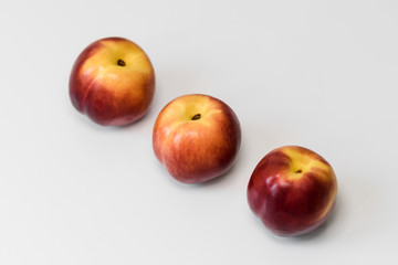 Ripe red nectarines, peaches, apples on a white table. Tasty bright fruits. Isolated object.