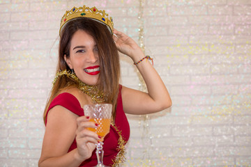 Funny woman who enjoys celebrating the new year with a golden crown and a glass of champagne in her hand.