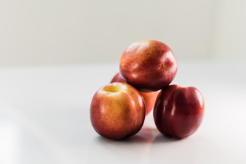 Ripe red nectarines, peaches, apples on a white table. Tasty bright fruits. Isolated object.